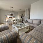 Wohnzimmer mit Sofa, Esstisch und Küche im Hintergrund.
