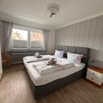 Schlafzimmer mit Doppelbett, Kleiderschrank und Fenster mit Blick auf Dächer.