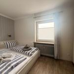 Zimmer mit Doppelbett, Fenster und Kleiderschrank.