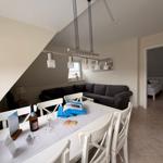 Essbereich mit Tisch und Stühlen, Wohnzimmer mit Sofa und Schlafzimmer im Hintergrund.