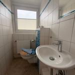 Badezimmer mit Waschbecken, Spiegel, Toilette und Fenster