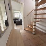 Haus mit Treppe und Spiegel. Wohnzimmer mit Sofa und Fenster.
