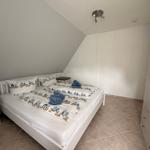 Schlafzimmer mit Doppelbett, Nachttisch und Kleiderschrank unter schräger Decke.