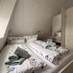 Zimmer mit zwei Betten, Spiegeltüren und Dachschrägen.