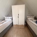 Zwei Betten und ein Schrank in einem Dachzimmer mit Holzboden.