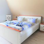 Schlafzimmer mit Doppelbett, Nachttischen und Bettwäsche.