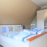 Schlafzimmer mit Bett, Kleiderschrank und Stuhl