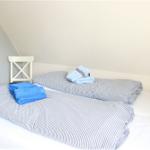 Schlafzimmer mit Doppelbett, gestreifter Bettwäsche und blauen Handtüchern.