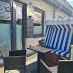 Terrasse mit Liegestuhl, Tisch und Stühlen vor Hauswand.