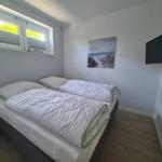 Schlafzimmer mit Doppelbett, Wandbild und Fernseher.