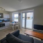 Wohnküche mit Essbereich, Sofa und TV. Glastür führt auf Balkon.