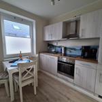 Küche mit Essbereich, hellen Schränken und Küchenzeile mit Herd und Spüle.