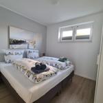 Schlafzimmer mit Doppelbett, Fenster und Kleiderschrank.