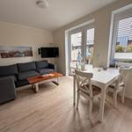 Wohn- und Essbereich mit Sofa, TV und Tisch mit Stühlen.