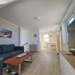 Living room with sofa, coffee table, and TV. Passage to dining area with table and chairs.
