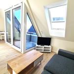 Wohnzimmer mit Sofa, TV und Balkontür. Holzdielen und Fenster.