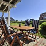 Terrasse mit Tisch und Stühlen, Blick auf Garten und Häuser.