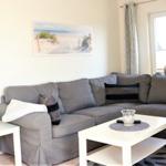 Ein Wohnzimmer mit grauem Sofa, weißem Couchtisch und Wandbild an der Wand.