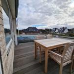 Terrasse mit Holztisch und Stühlen, Blick auf Häuser und Wasser.