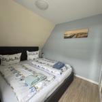 Schlafzimmer mit Doppelbett, Wandbild und Kleiderschrank.