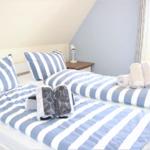 Schlafzimmer mit Doppelbett, gestreiften Bettwäsche und Fenster.