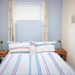 Two beds with striped bed linen, nightstands with lamps, and window with curtains.