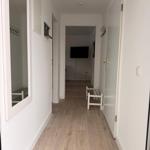 Hallway with wooden floor, mirror, hooks, and bench.