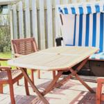 Terrace with wooden table, four chairs, and beach chair with blue-white stripes.