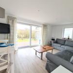 Living room with sofa, TV, and view of the garden.