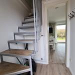 Staircase with wooden steps and view into living area with table and chairs.