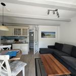 Wohn- und Küchenbereich mit Sofa, Tisch und Küchenzeile.