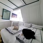 Schlafzimmer mit Bett, Spiegel und Fenster. Dachbodenraum mit weißen Wänden.