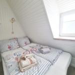 Schlafzimmer mit Dachschräge, Bett mit Bettwäsche und Fenster.