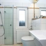 Badezimmer mit Dusche, Waschbecken und Toilette. Fenster mit Blick nach draußen.