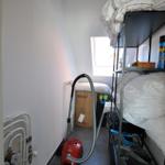 Schlafzimmer mit Hochbett, Staubsauger und Fenster.