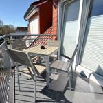 Terrasse mit Tisch und Stühlen, Blick auf Haus und Straße.