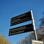 Schild weist auf Touristeninformation, Wellenpark, Erlebnisbad Ocean Wave, Abenteuergolfpark und Kinderspielhaus.