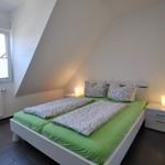 Schlafzimmer mit Doppelbett, grüner Bettwäsche und zwei Nachttischen mit Lampen.