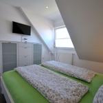 Schlafzimmer mit Doppelbett, TV und Fenster unter Dachschrägen.