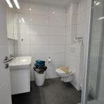Badezimmer mit Dusche, Toilette, Waschbecken und Handtüchern.
