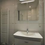 Badezimmer mit Waschbecken, Spiegel und Heizkörper an der Wand.