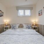 Schlafzimmer mit Bett, Nachttischen und Wandbildern an den Wänden.