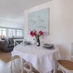 Dining table with tablecloth, flowers, and wine. Living area with sofa and TV.
