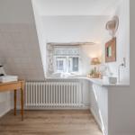 Bathroom with sloped ceiling, window, sink, and wooden table.