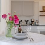 Table with flowers, dishes, and bottle in kitchen