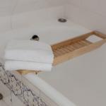 Bathtub with wooden tray and folded white towels.