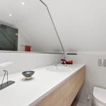 Moderne Dusche mit Glaswand, Waschbecken und Toilette unter schrägem Dach