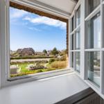 Weitblick aus dem Fenster auf grünen Garten und Ferienhaus.