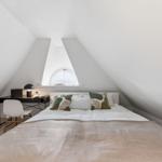 Schlafzimmer mit Dachschräge, Bett, Schreibtisch und Fenster