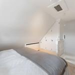 Schlafzimmer mit Dachschrägen, weißem Bett und Kleiderschrank